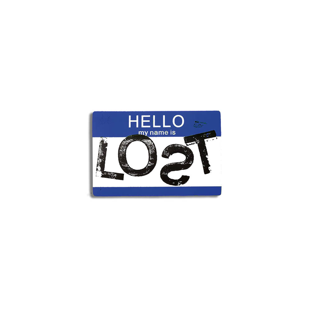 Hello my name is LOST sticker. A blue and white nametag sticker stamped with the name LOST with a backwards S. The sticker is set against a plain white Background.