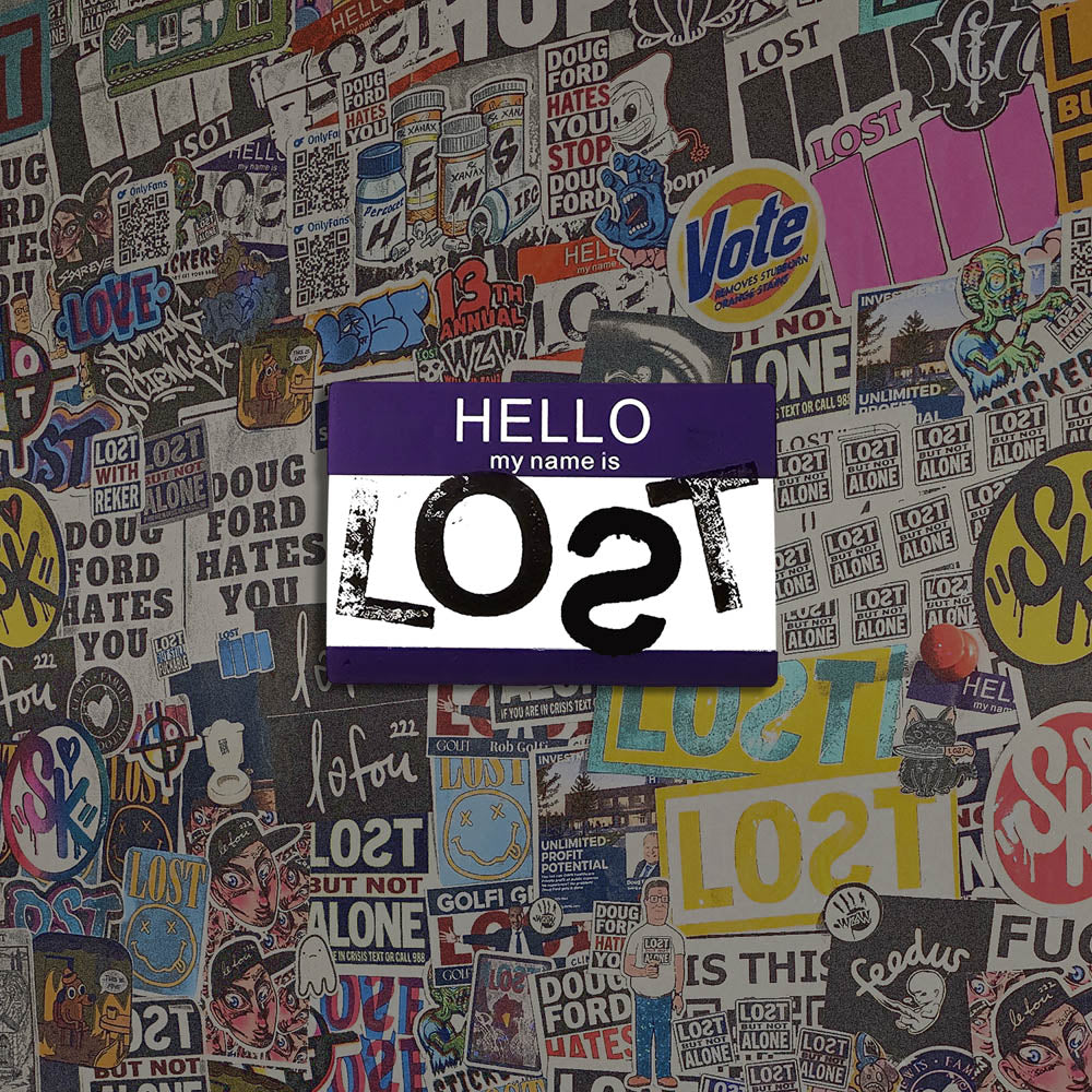 Hello my name is LOST sticker. A purple and white nametag sticker stamped with the name LOST with a backwards S. The sticker is set against a colorful wall of graffiti stickers.
