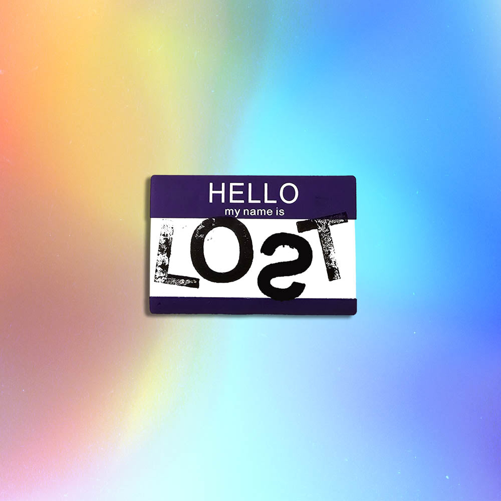 Hello my name is LOST sticker. A purple and white nametag sticker stamped with the name LOST with a backwards S. The sticker is set against a holographic background.