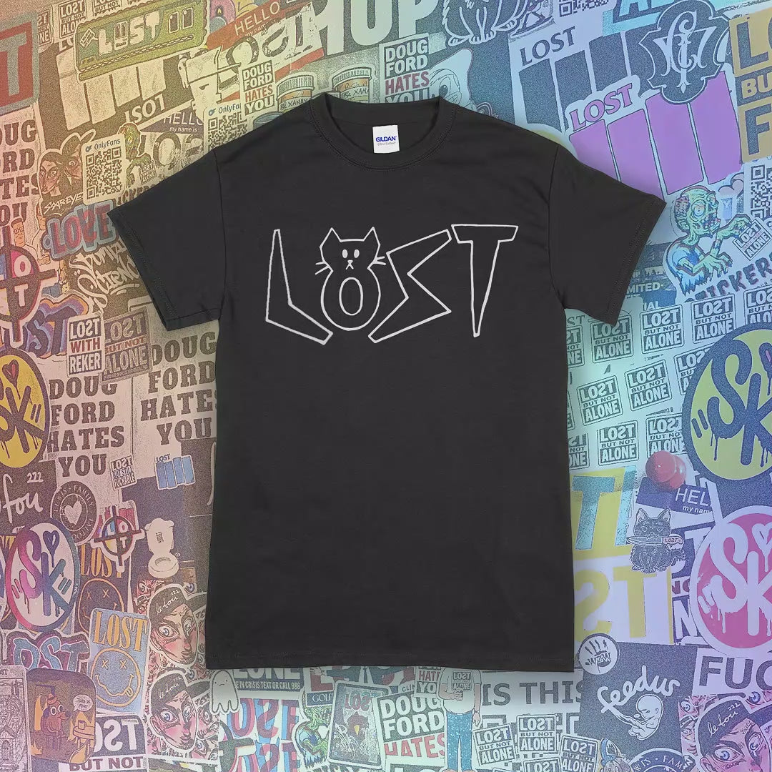 Charlottes White Cat Letter design. Hand drawn design of cat shaped letters. Drawn by my daughter Charlotte, and printed with white ink on a different colored shirts. Graffiti stickers in the background. 